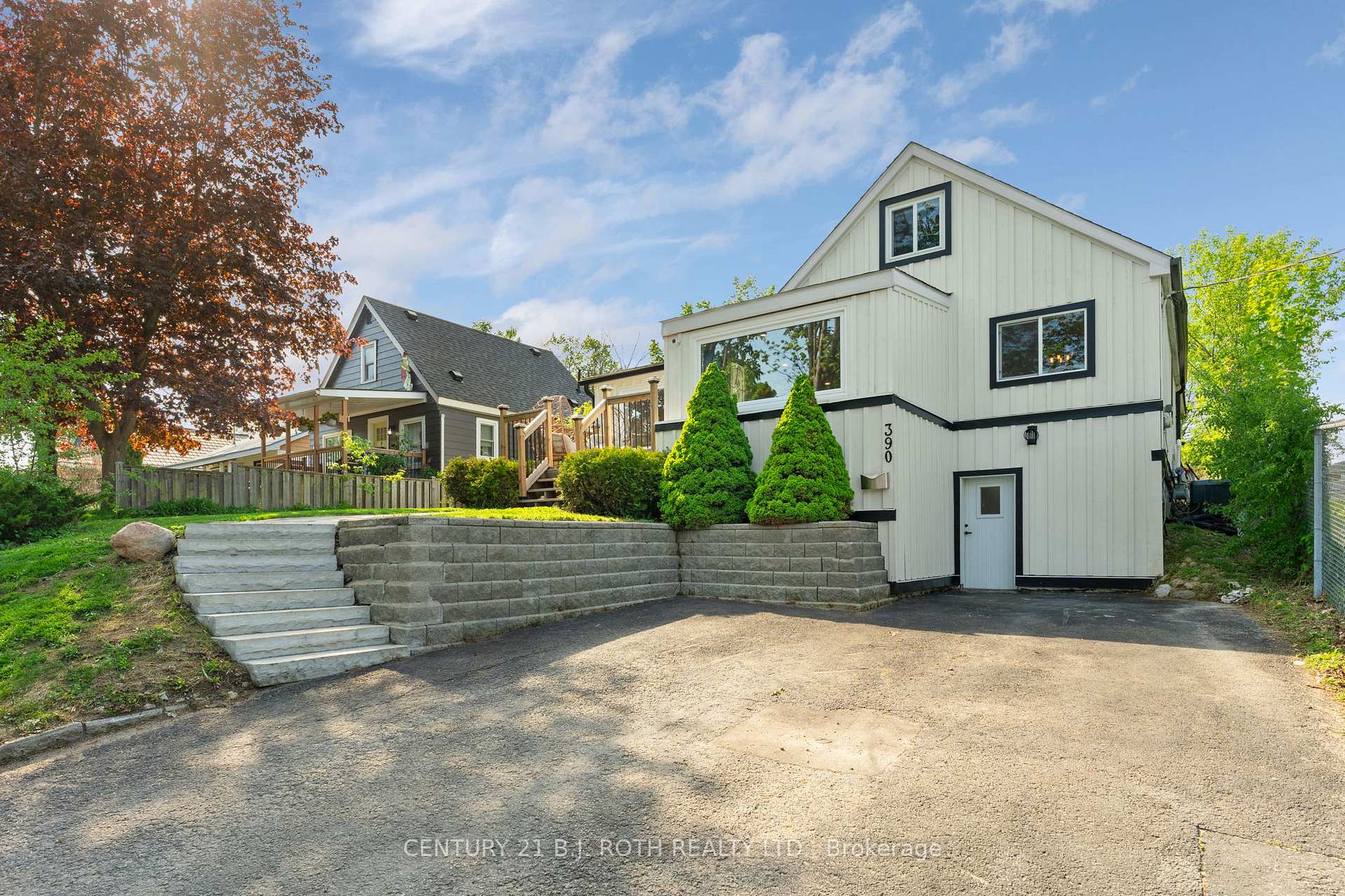 White two-story house with black trim, broad retaining wall steps, and landscaped front yard.