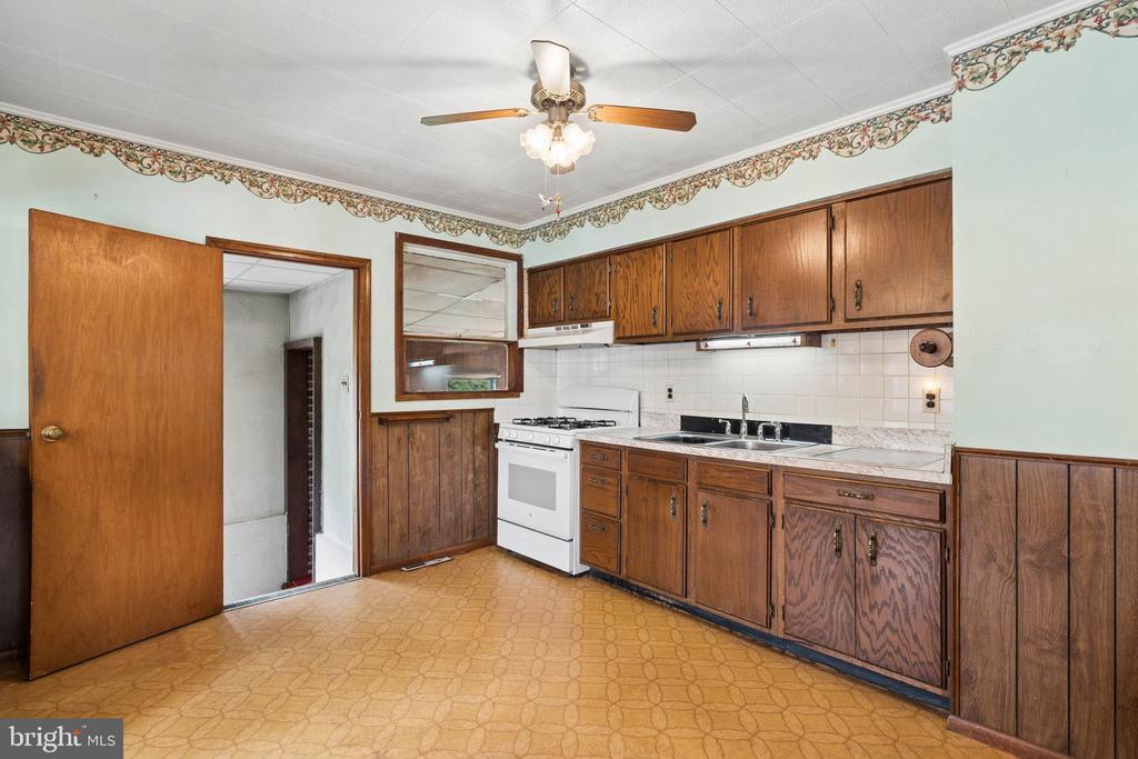 Kitchen with wood cabinets, a white gas range, and patterned flooring.