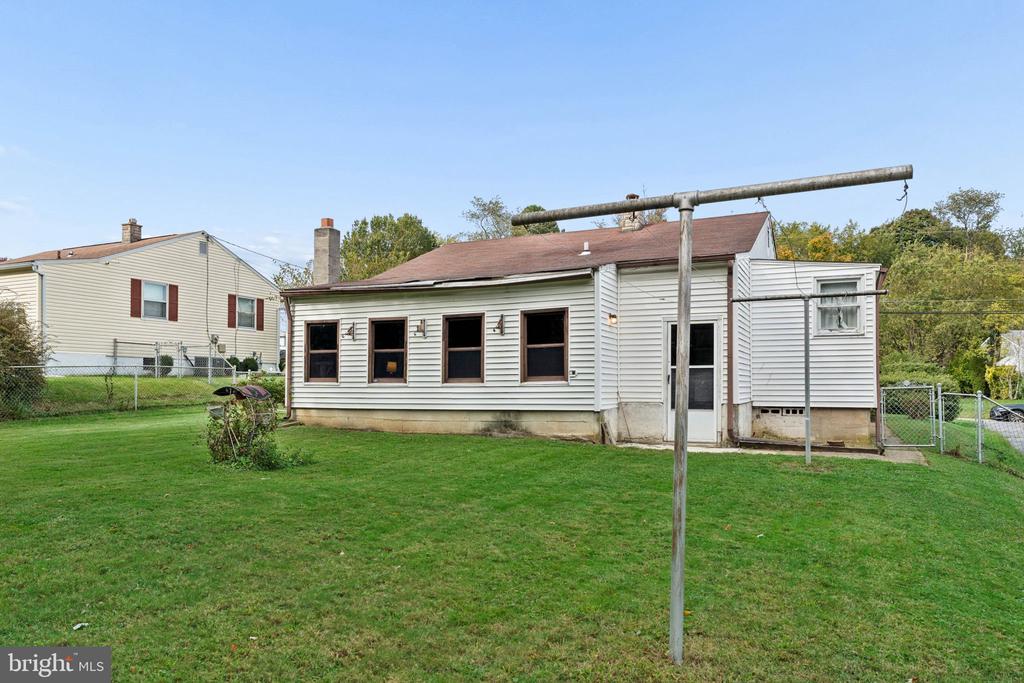 Rear of a single-story house with a broad lawn and overhead clothesline.