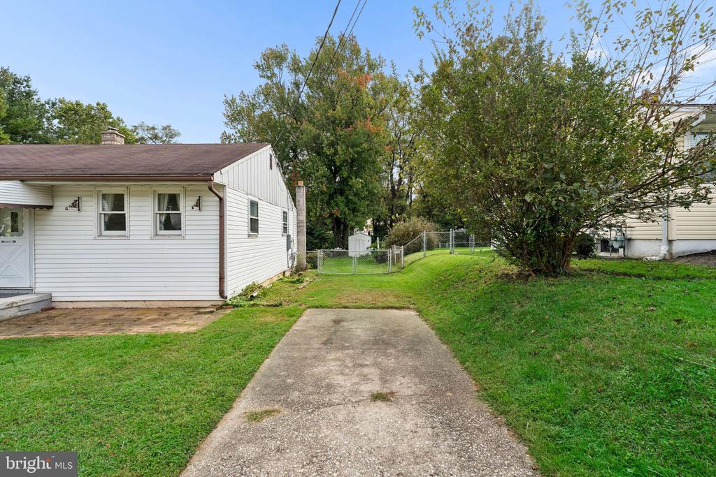 White single-story house beside a concrete driveway and fenced backyard.