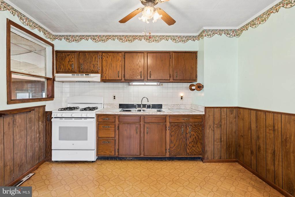 Kitchen with wood cabinets, white stove, sink, and patterned flooring.