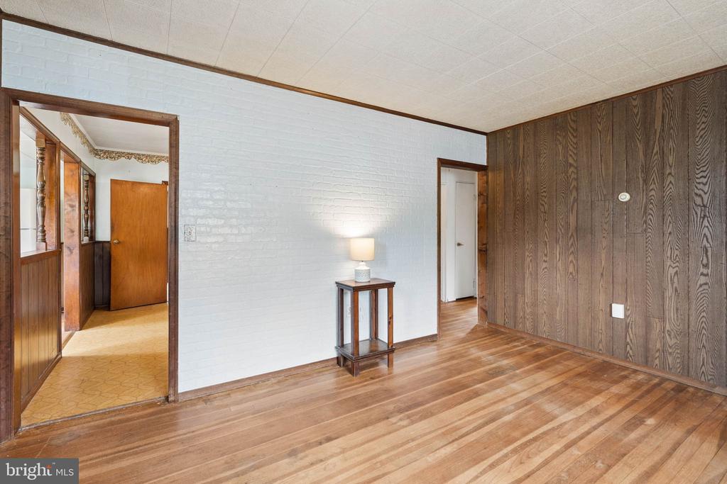 Living room with hardwood floors, a white brick wall, and dark wood paneling.