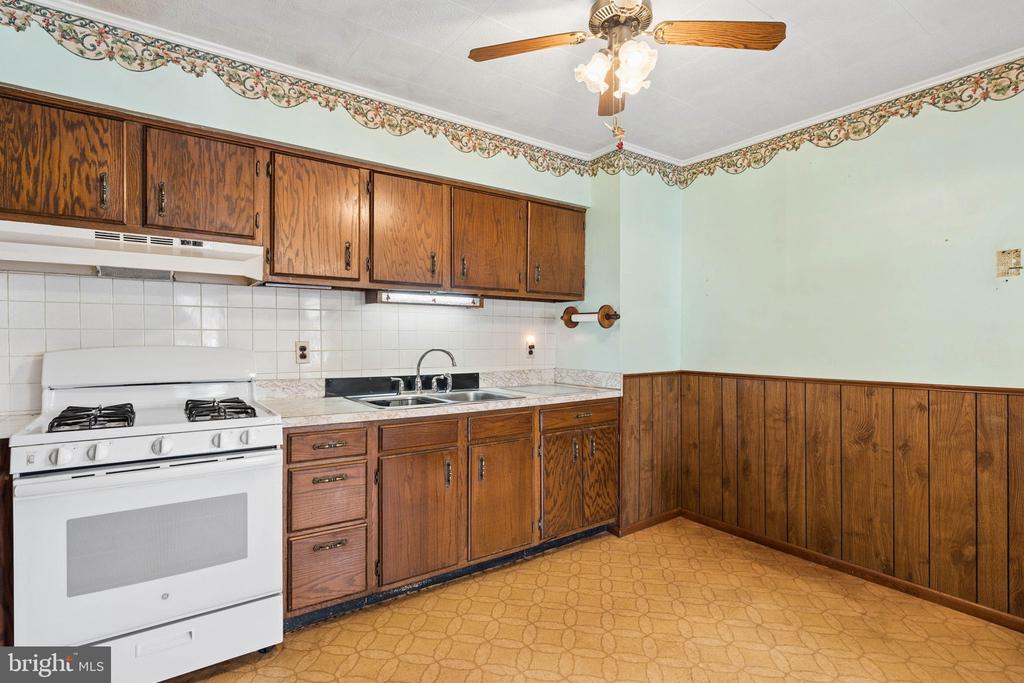 Kitchen with dark wood cabinets, white range, and patterned linoleum floor.