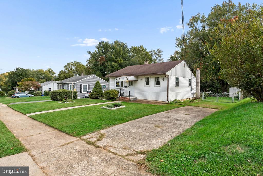 White single-story home with a brown roof, front lawn, and driveway.