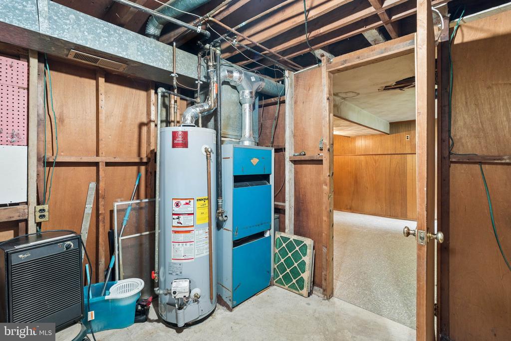 Unfinished basement utility room with a water heater, furnace, and exposed framing.