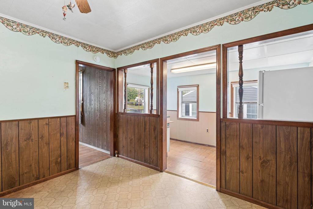 Interior with wood-paneled lower walls, patterned flooring, and wide openings into adjoining rooms.