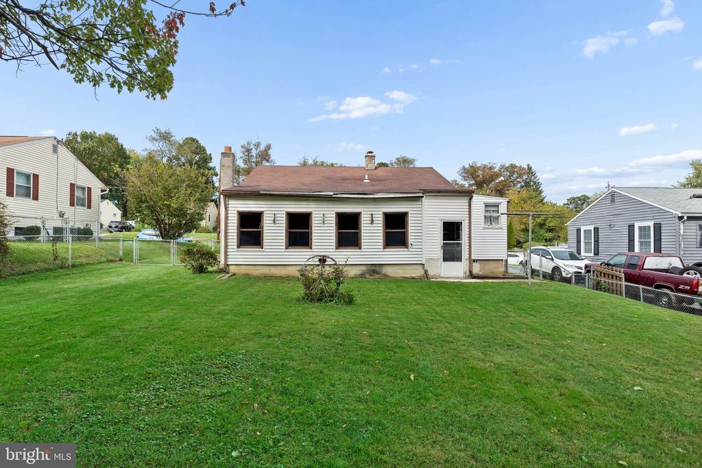 Rear of a single-story home with a fenced lawn and neighboring houses.