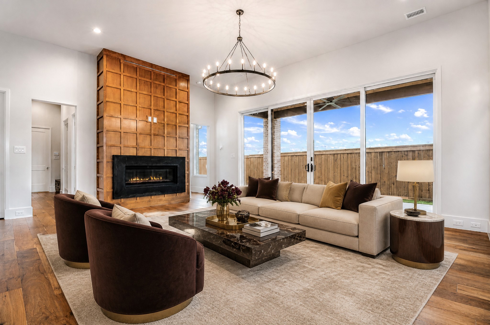 Living room with a wood-paneled fireplace, marble coffee table, and sliding glass doors to a fenced patio.