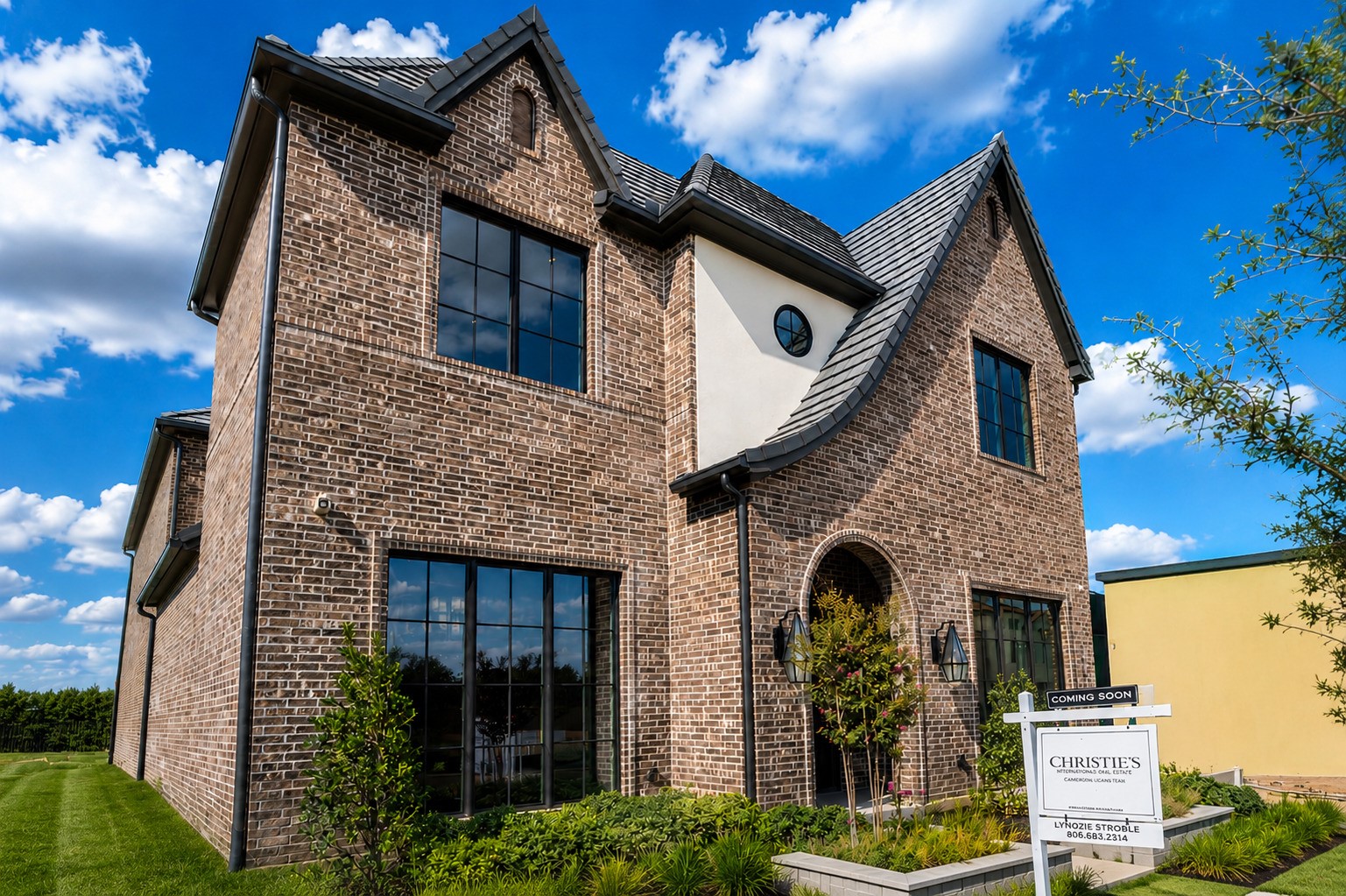 Two-story brick home with a dark tiled roof, black-framed windows, and an arched front entry.