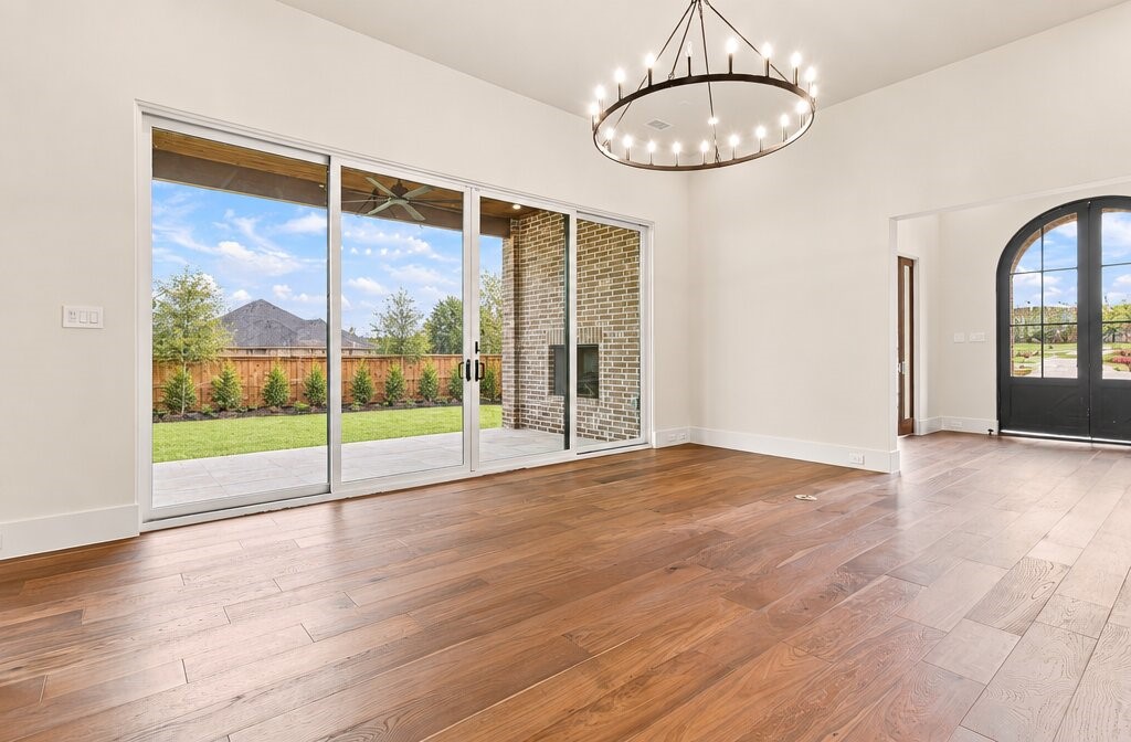 Vacant room with hardwood floors, a circular chandelier, and sliding glass doors to the backyard.