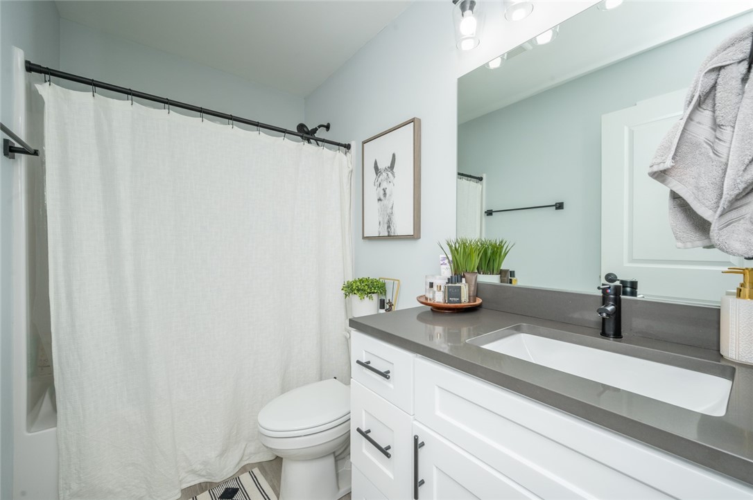 Bathroom with a white vanity, gray countertop, large mirror, and shower curtain.
