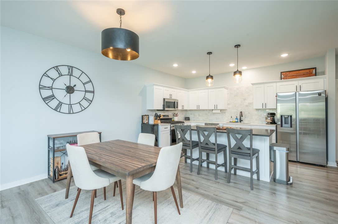 Open-plan kitchen and dining area with white cabinets, stainless appliances, and a wood dining table.