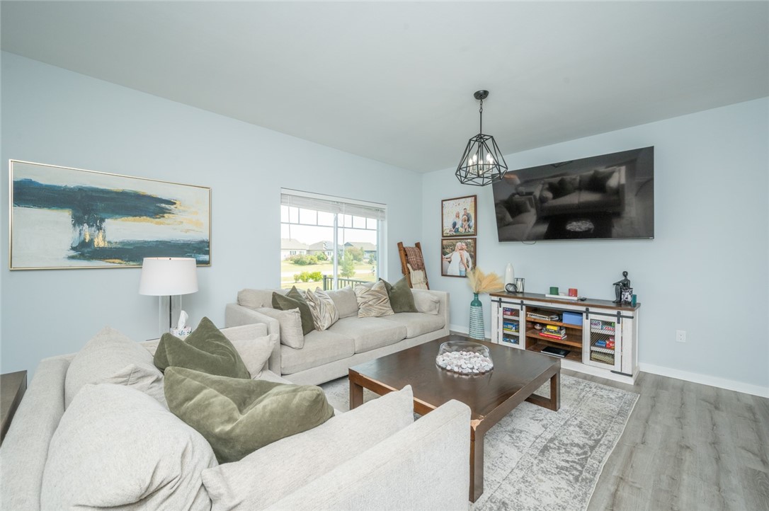 Furnished living room with light sofas, olive pillows, a wood coffee table, and a large window.