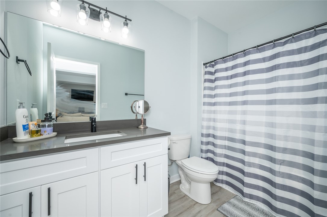 Bathroom with a long white vanity, gray countertop, and striped shower curtain.