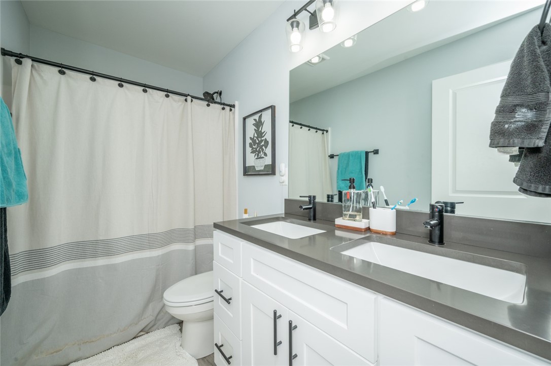 Bathroom with a double-sink vanity, large mirror, and striped shower curtain.