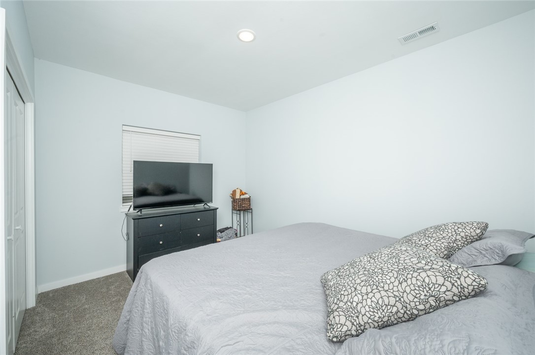 Bedroom with a large bed, patterned pillows, and a television on a dresser.