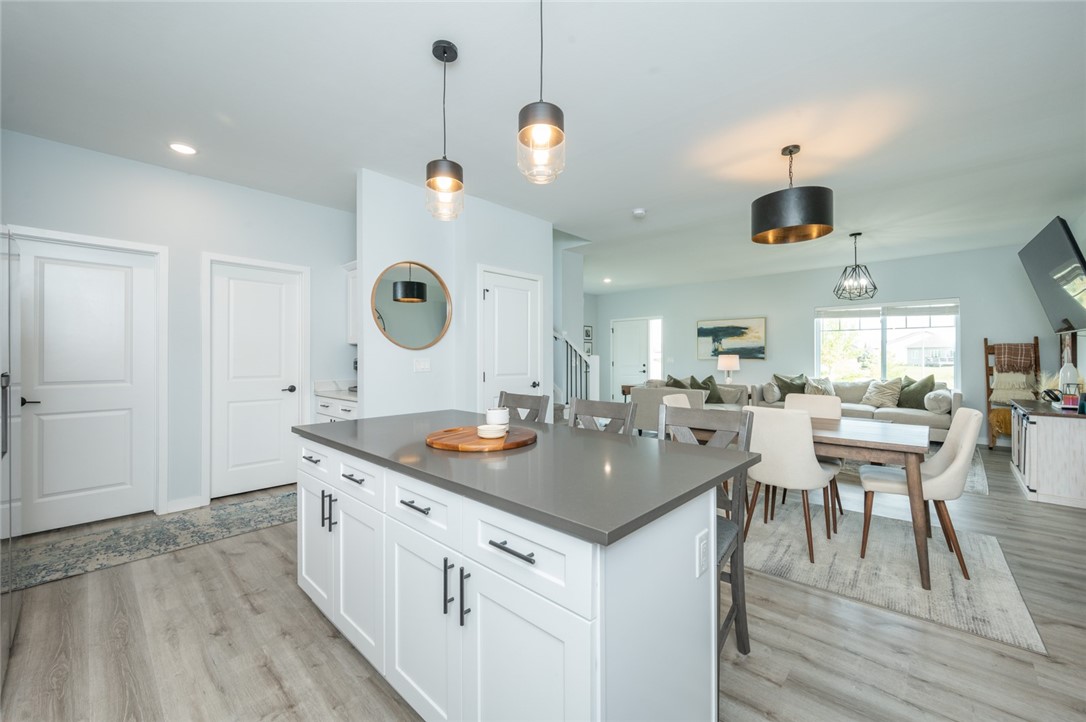 Open-plan kitchen with a large gray island, dining table, and living area beyond.