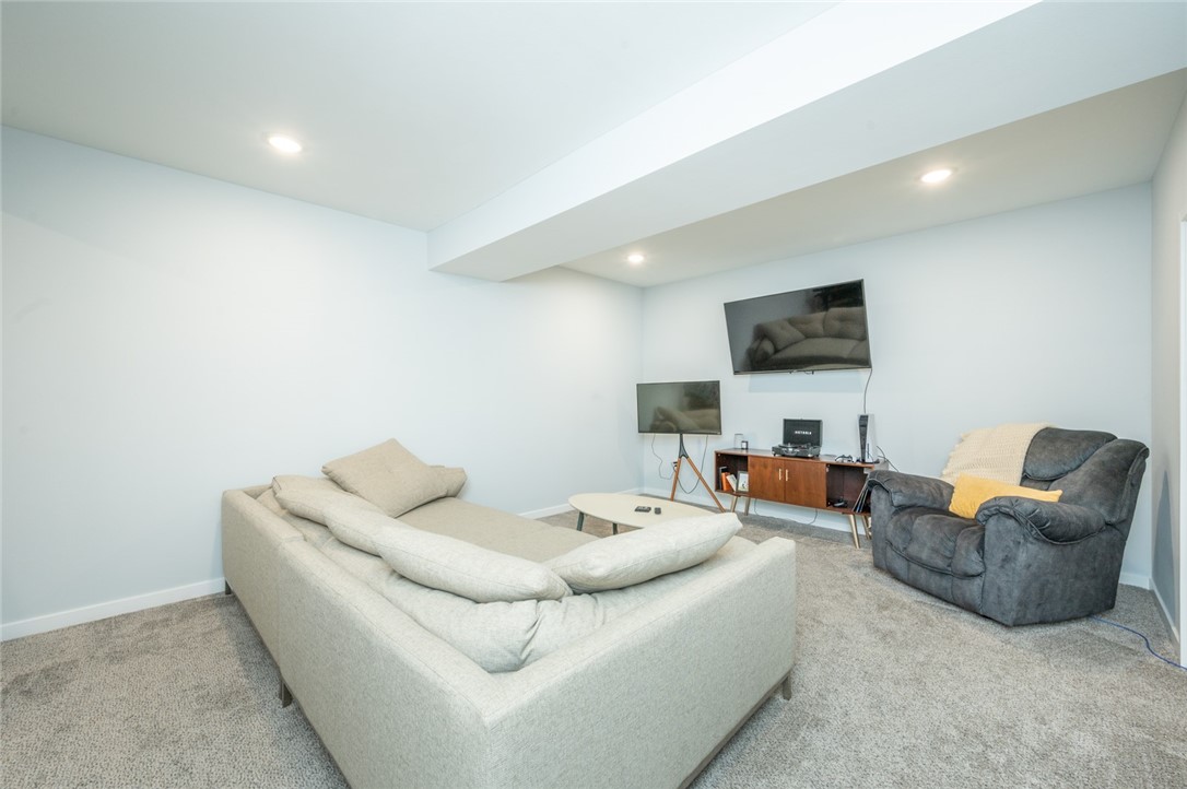 Furnished basement living room with a large sectional, gray recliner, and two televisions.