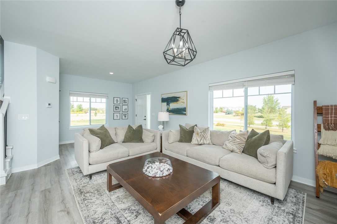Living room with two light sofas, a dark wood coffee table, and large windows overlooking a green yard.