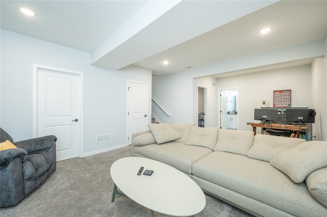 Living room with a large sectional sofa, oval coffee table, and desk with dual monitors.
