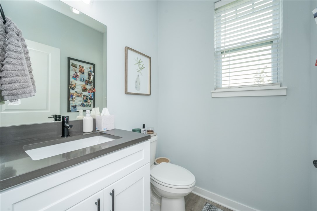 Bathroom with white vanity, dark countertop, and window with white blinds.
