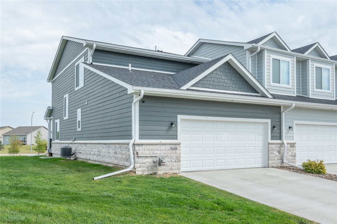 Gray attached home with stone veneer, white trim, and a double garage door.