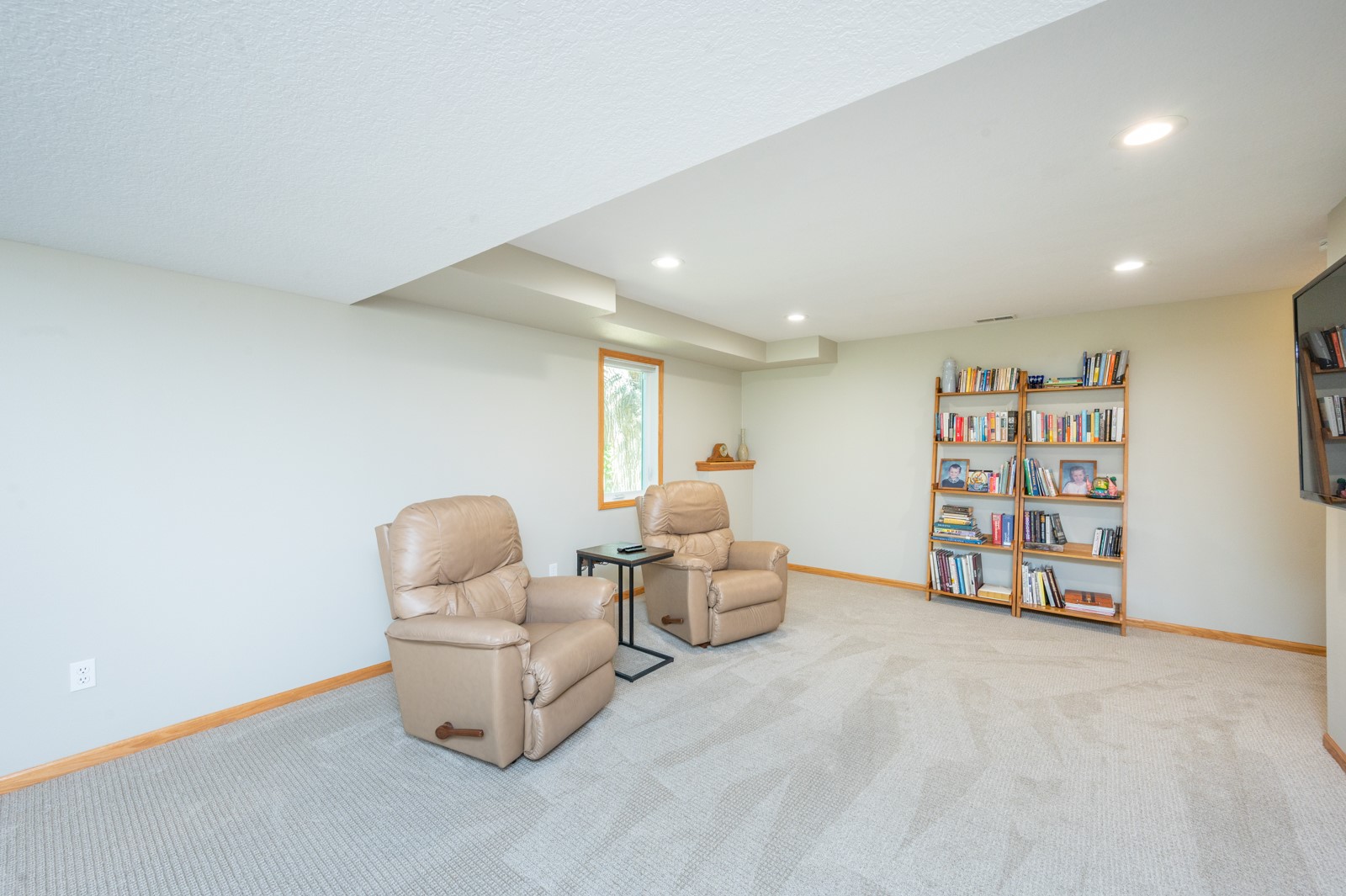 Living room with two tan leather recliners, wall-to-wall carpet, and bookcases filled with books.