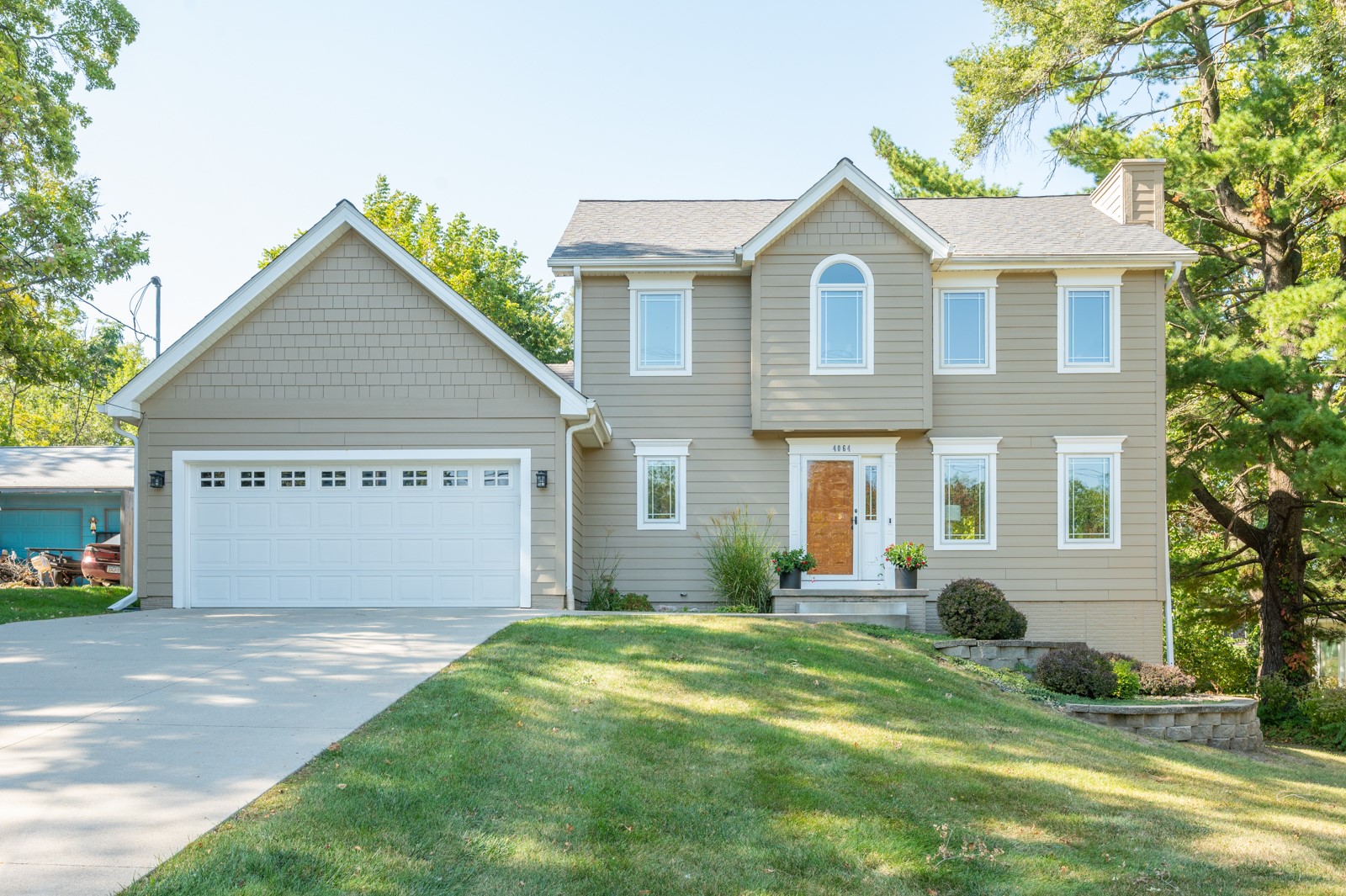 Two-story taupe house with white trim, a double garage, and an arched upper window.
