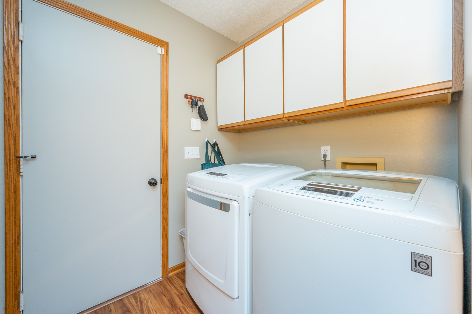 Laundry room with a washer and dryer beneath wood-trimmed cabinets.