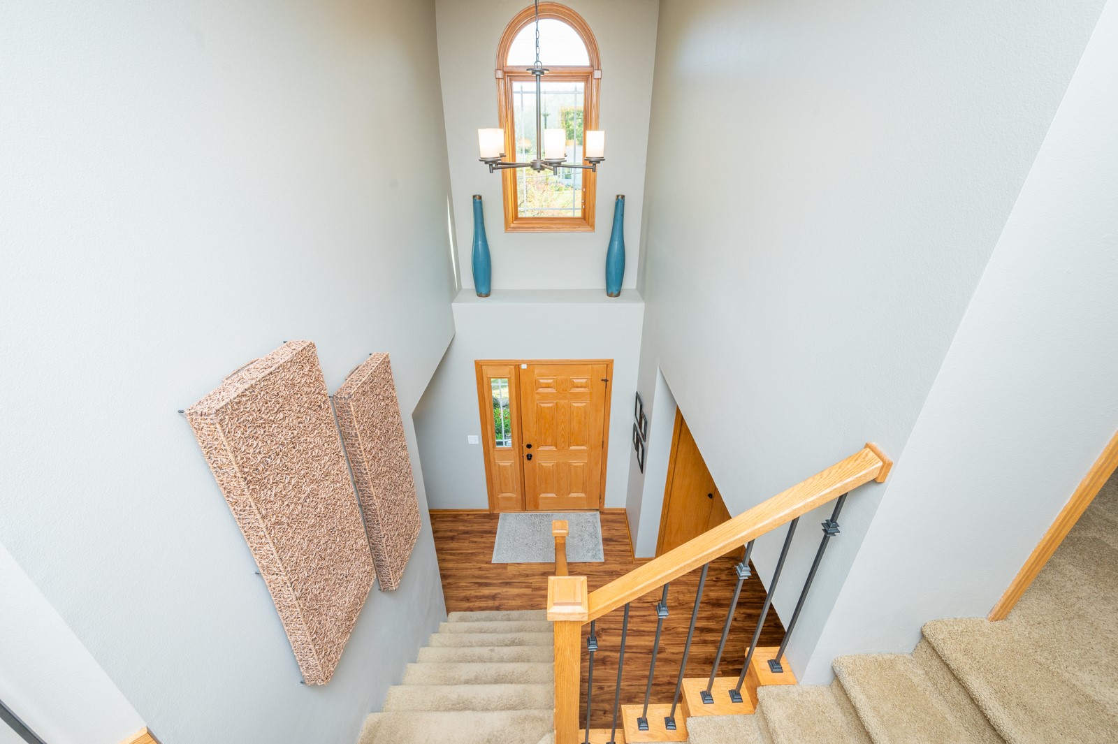 Two-story foyer with a carpeted staircase, wood handrail, and arched window above the front door.