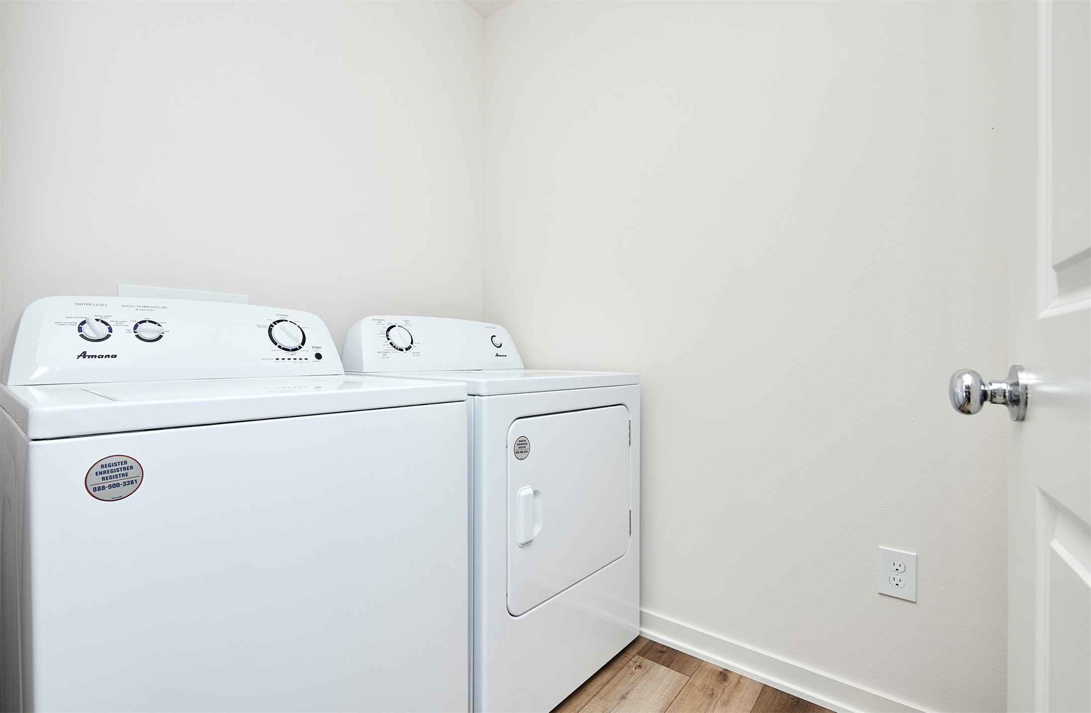 Laundry room with a white washer and dryer and wood-look flooring.