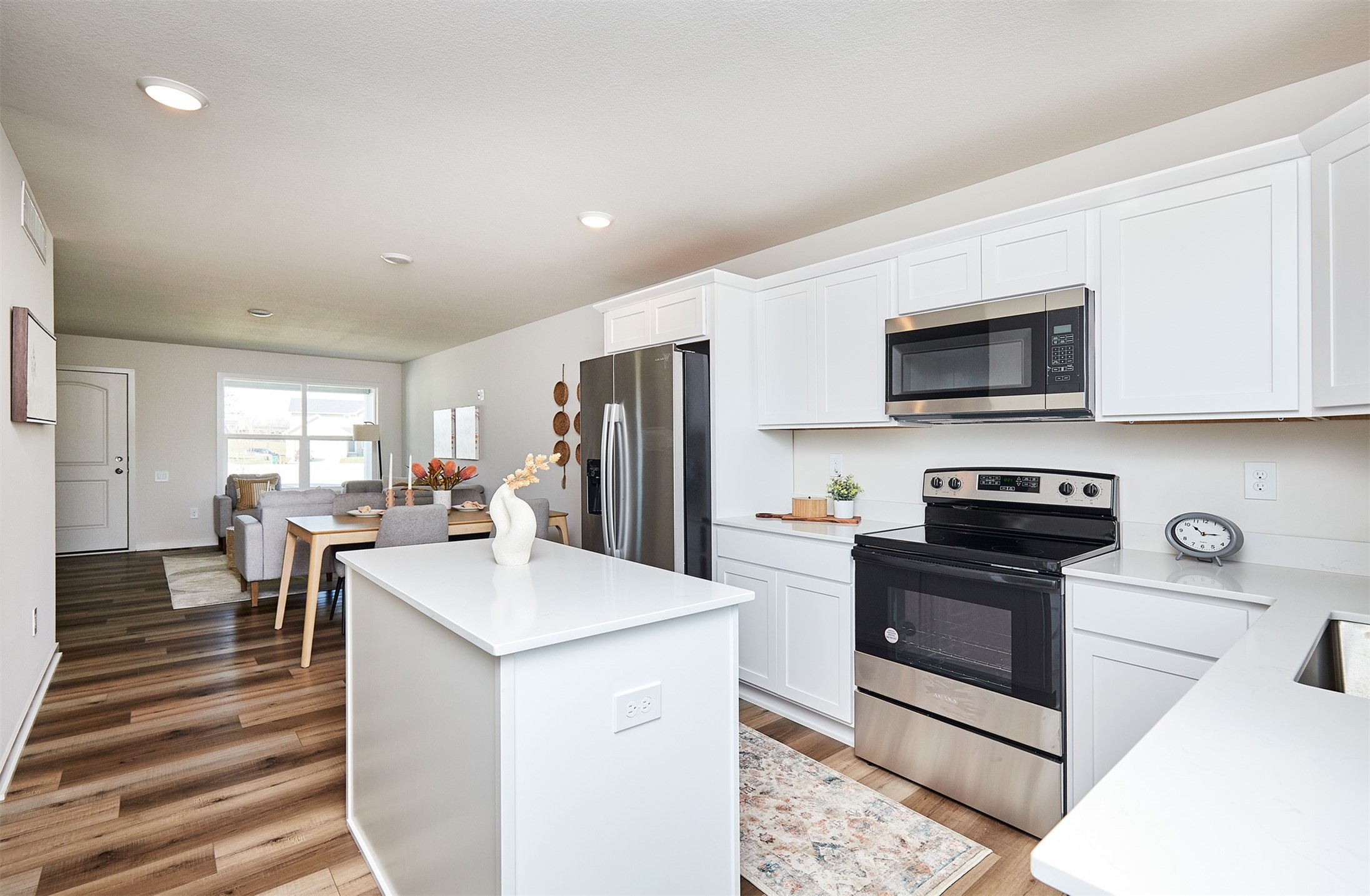 Open-plan kitchen with a large white island, stainless steel appliances, and dining and living areas beyond.