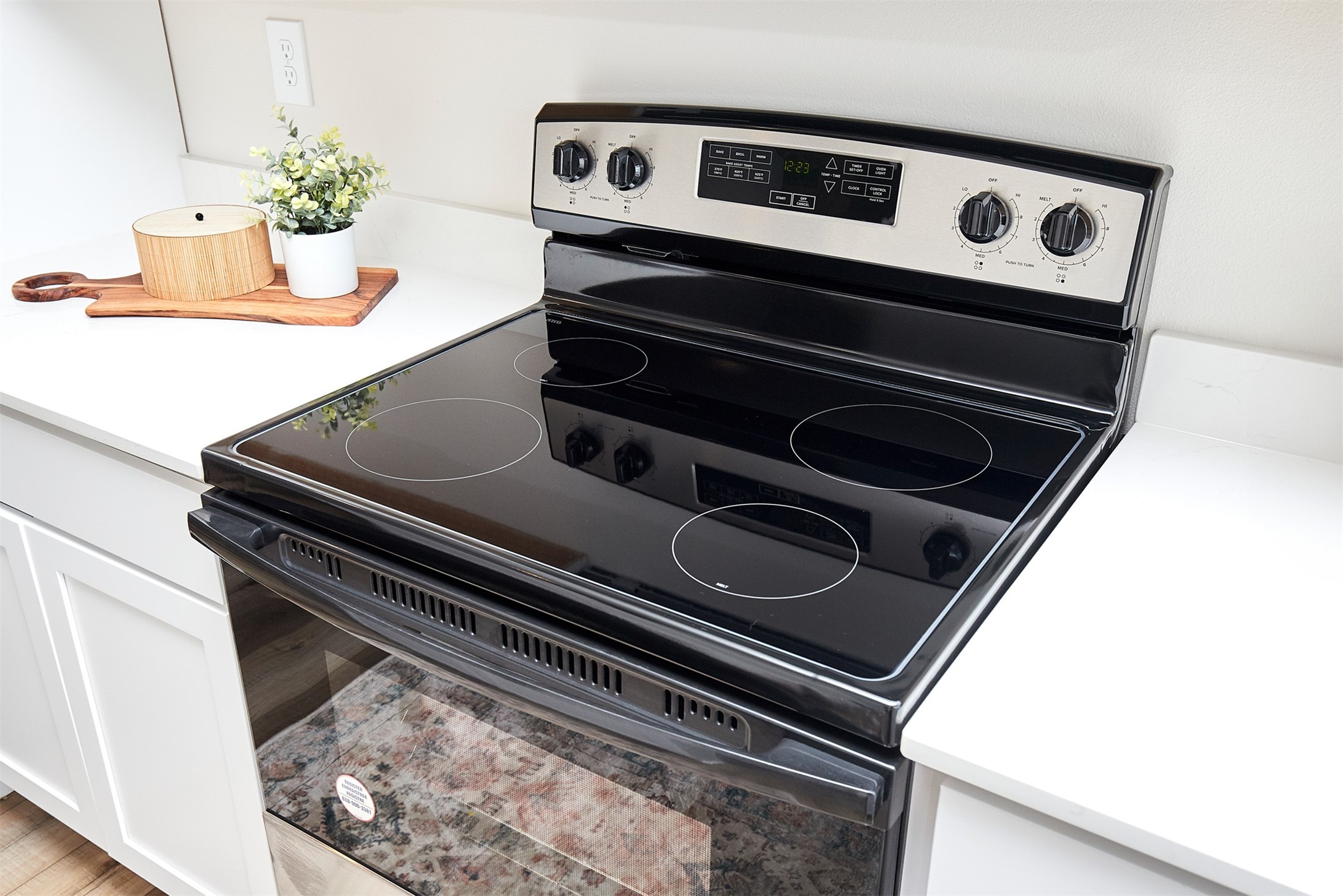 Black glass-top electric range with four burners between white kitchen counters.
