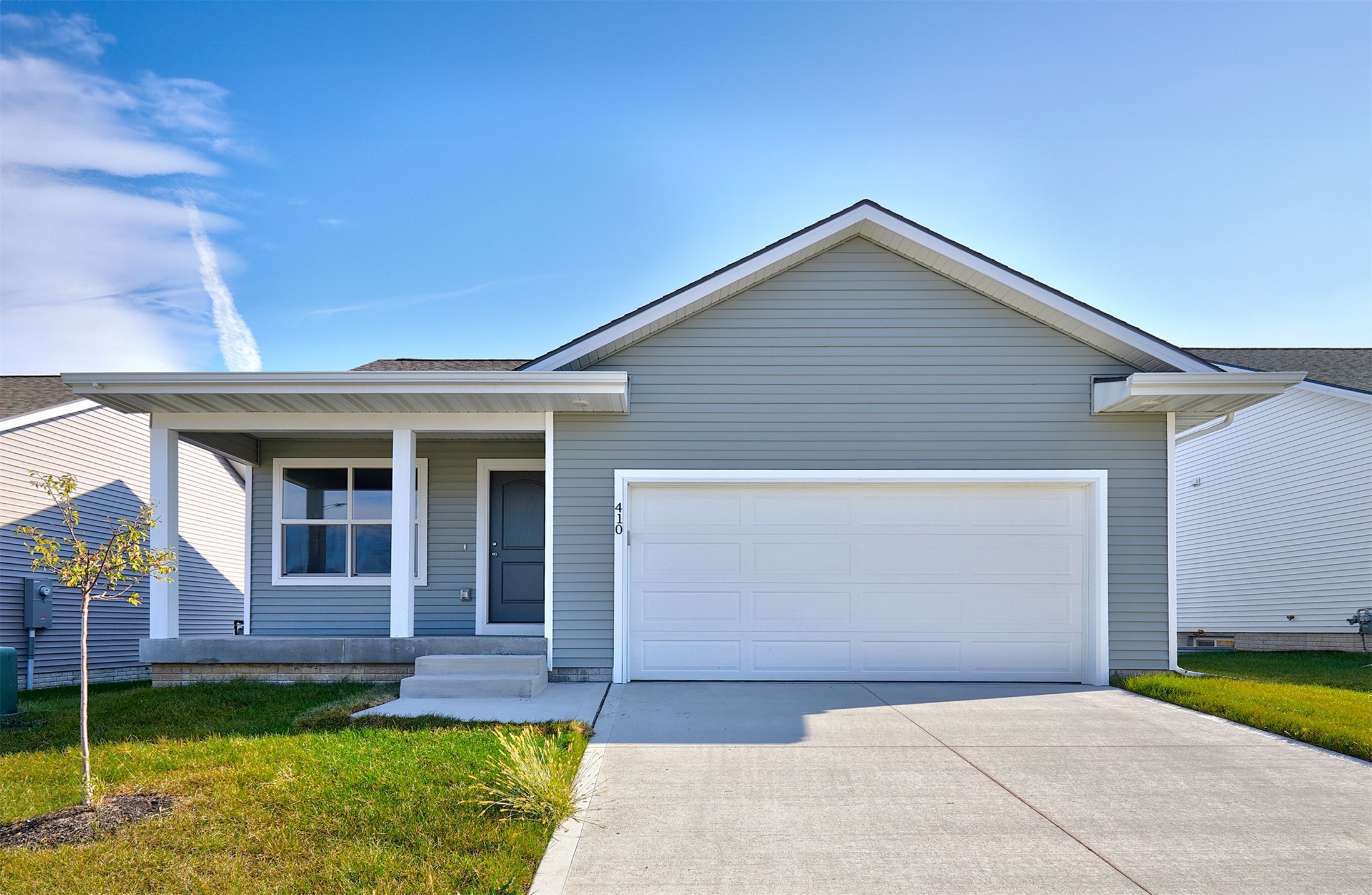 Gray single-story home with a covered porch, white two-car garage, and concrete driveway.