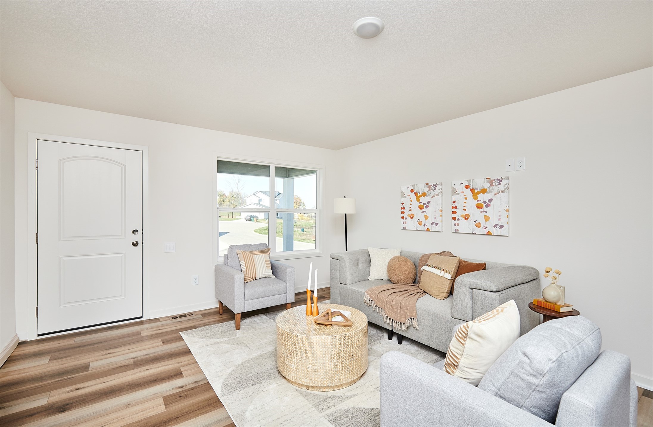 Furnished living room with gray seating, a round woven coffee table, and a large window.