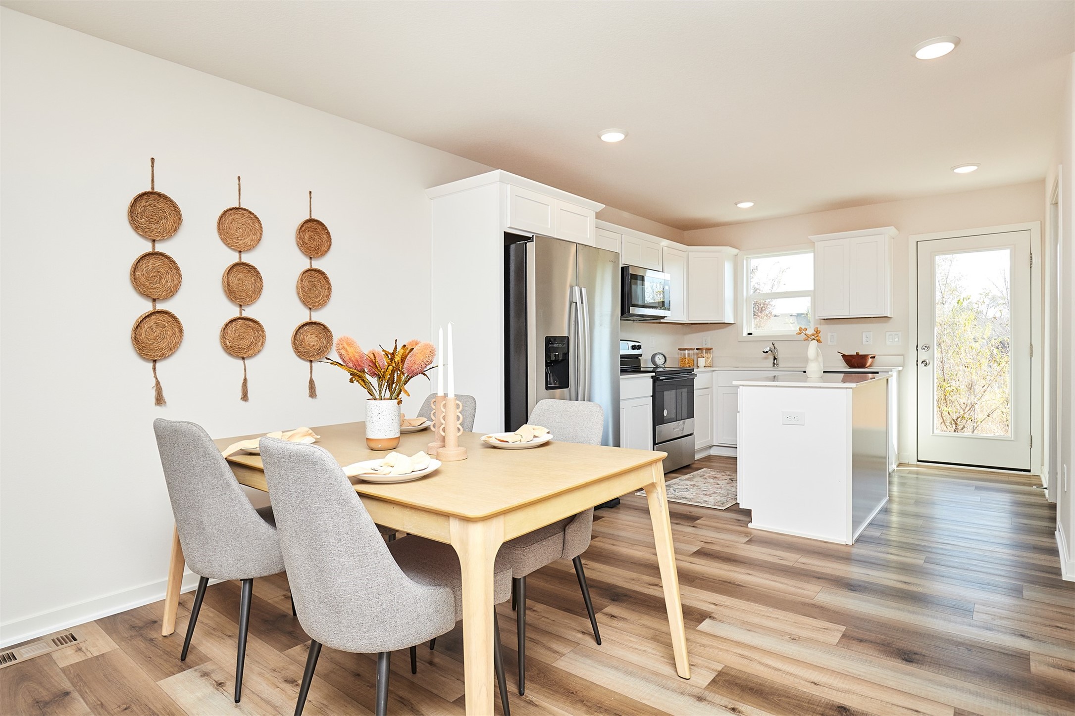Open-plan kitchen and dining area with white cabinets, stainless steel appliances, and a wood dining table.