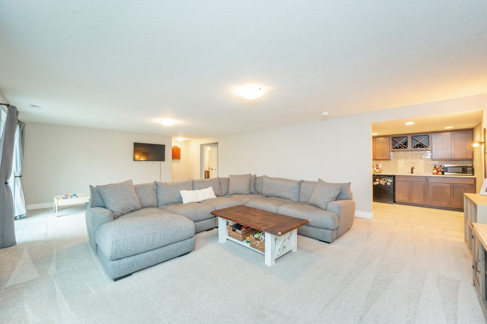 Living room with a large gray sectional and wood coffee table beside an open kitchen.