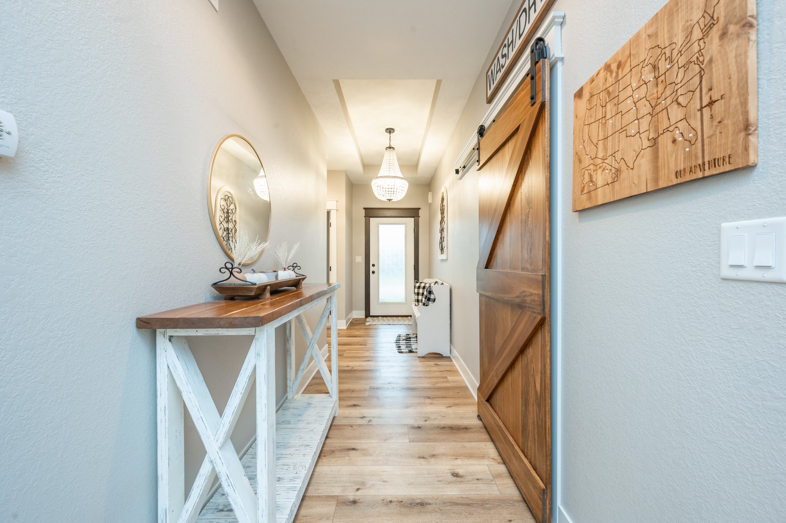 Entry hallway with wood plank flooring, a sliding barn door, and a crystal chandelier.