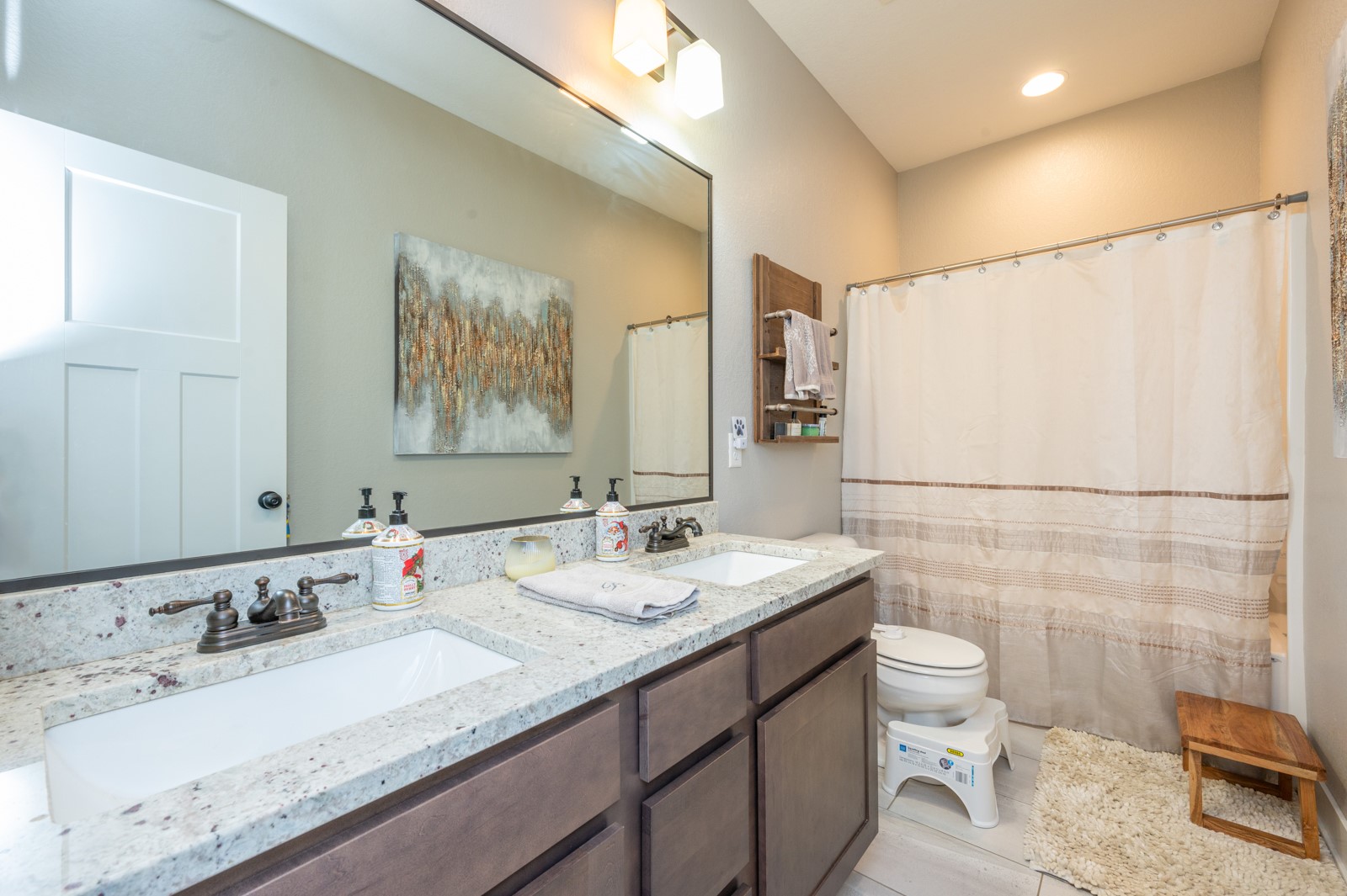 Bathroom with a double-sink stone vanity and a white shower curtain with beige trim.