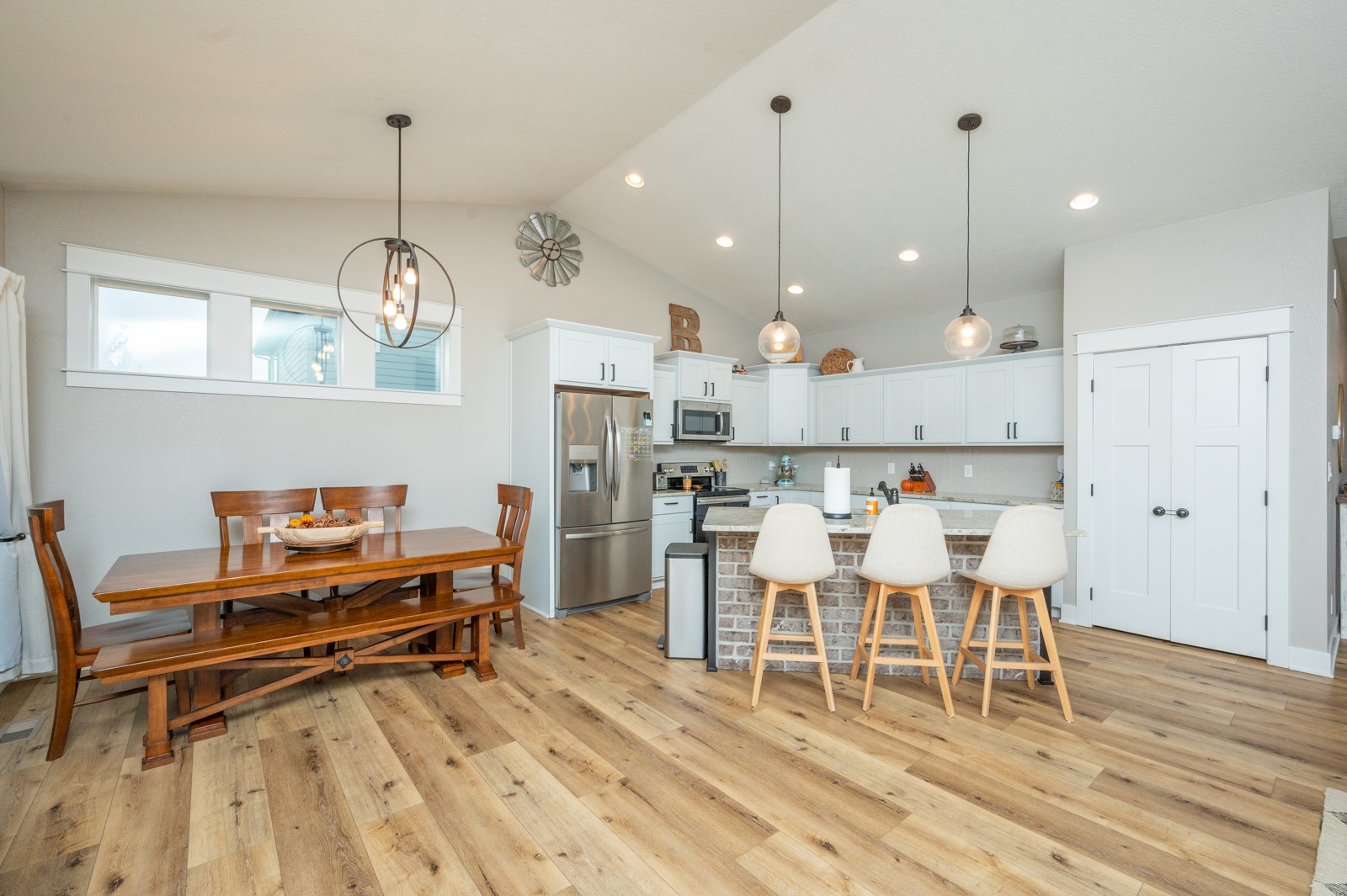 Open-plan kitchen and dining area with a brick-front island, white cabinetry, and a wooden dining table.