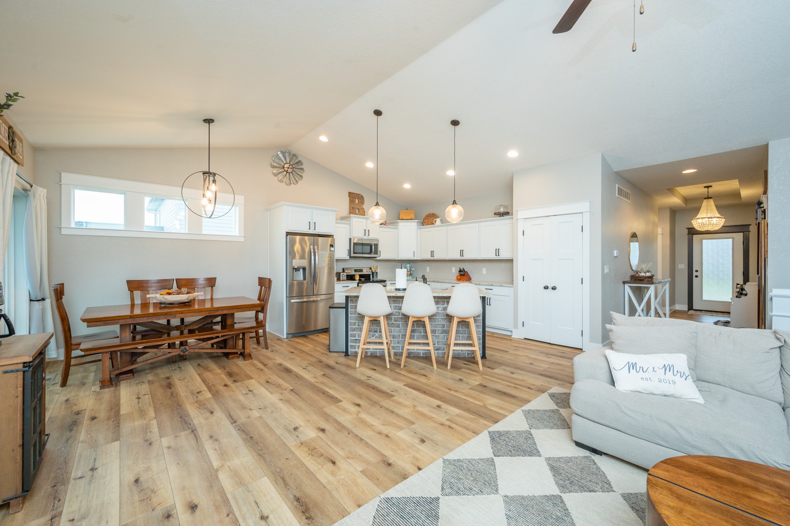 Open-plan kitchen and dining area with a brick-faced island, wooden table, and light wood floors.