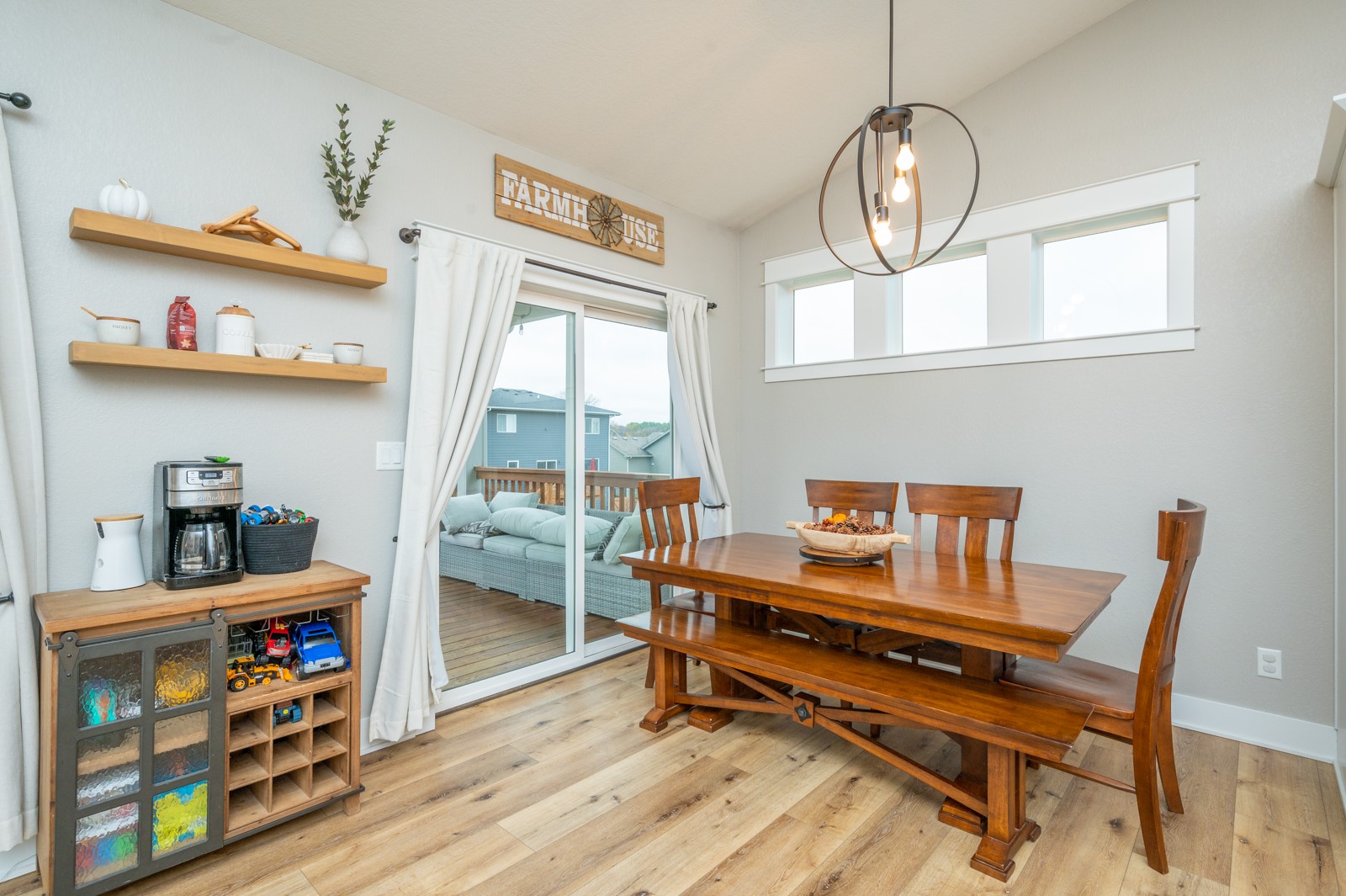 Dining room with a long wooden table, floating shelves, and sliding glass doors to a deck.