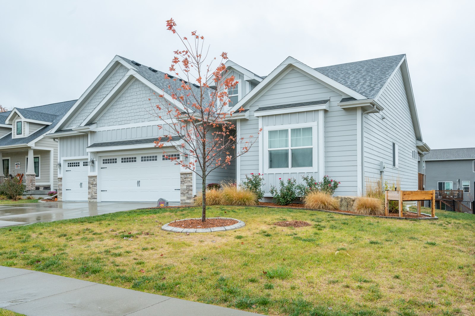 Gray-sided house with multiple gables, double garage, and an autumn tree in front.