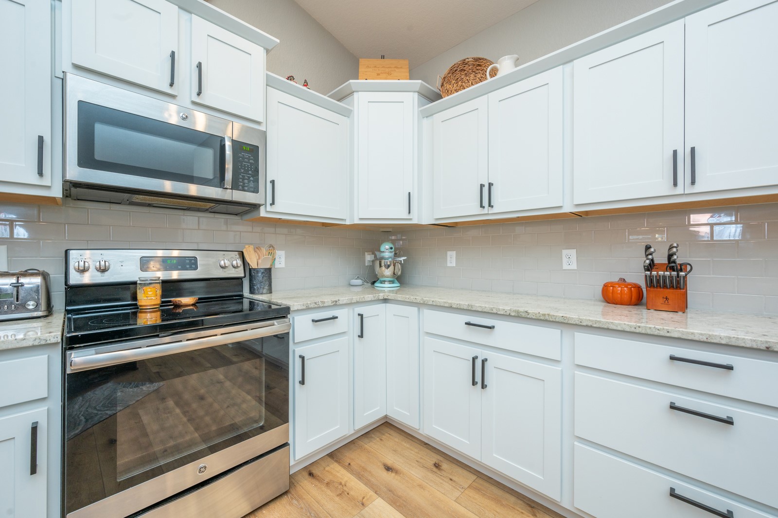 Kitchen with white shaker cabinets, stone counters, subway tile backsplash, and stainless steel appliances.
