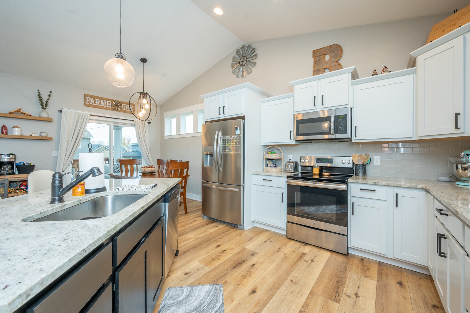 Bright kitchen with white cabinets, stainless appliances, stone counters, and a large island.