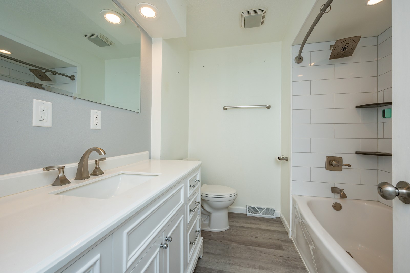Bathroom with a long white vanity and a subway-tile tub and shower.