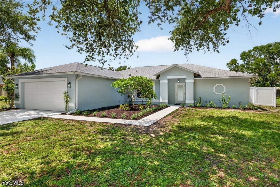 Single-story blue-gray home with a two-car garage, landscaped front beds, and a walkway to the entrance.
