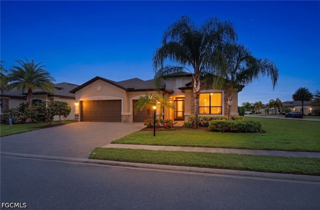 Florida home at dusk with a two-car garage, palm trees, and warmly lit windows.