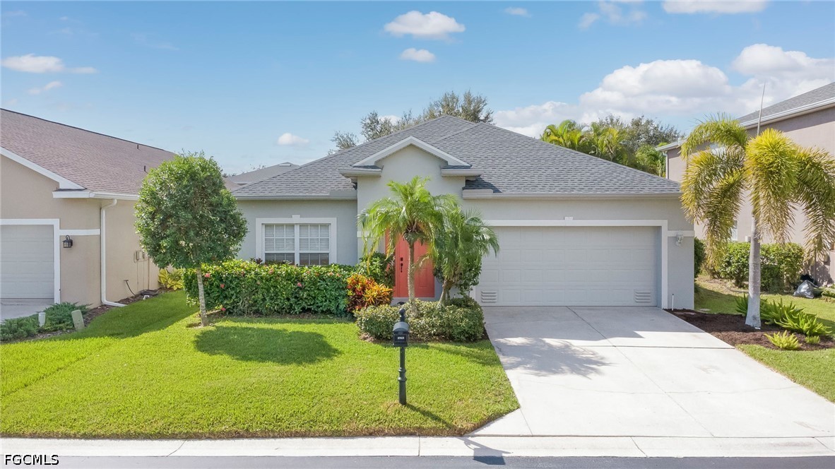 Single-story Florida home with a red front door, palm landscaping, and a two-car garage.