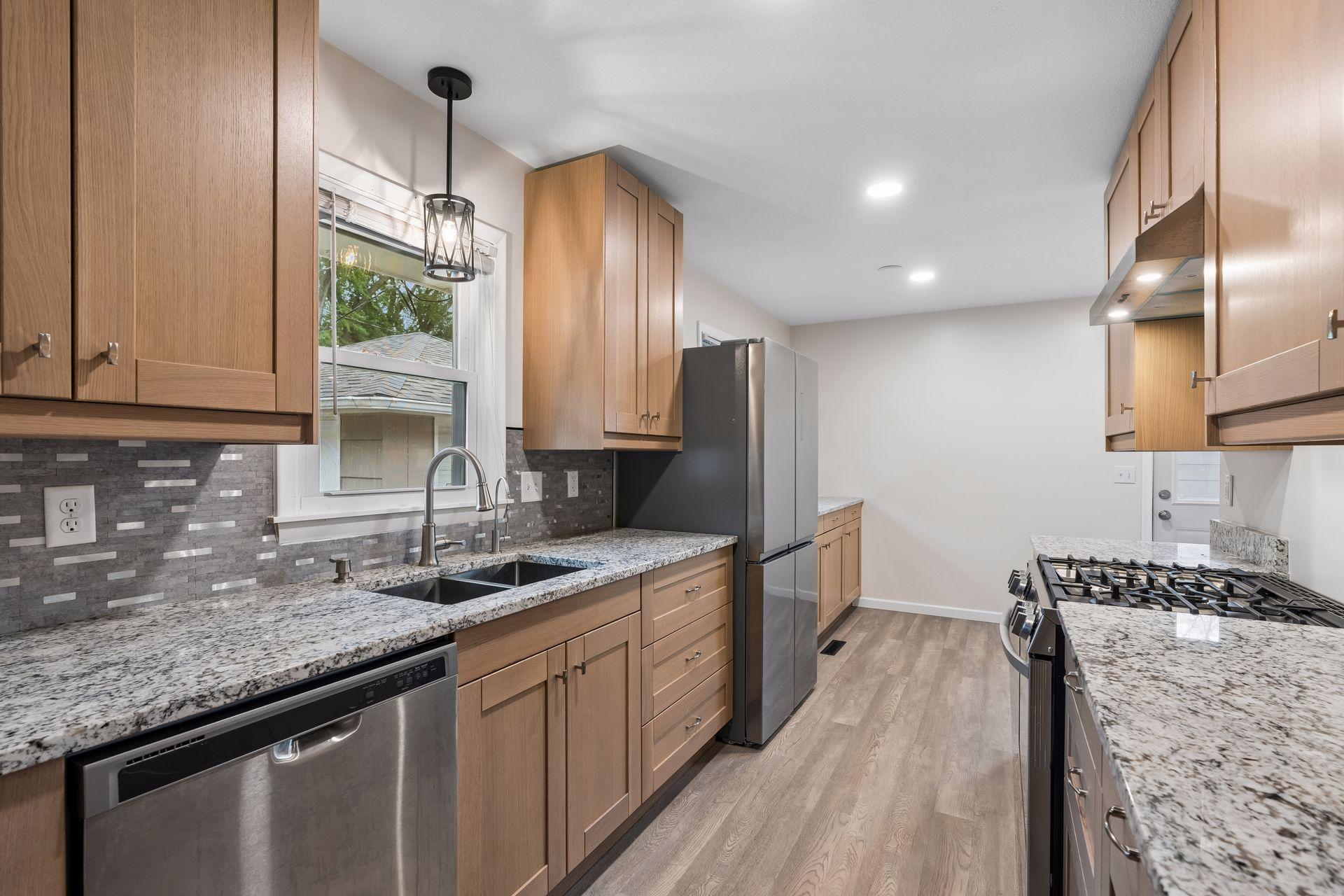 Renovated kitchen with wood cabinets, granite counters, stainless appliances, and a window over the sink.